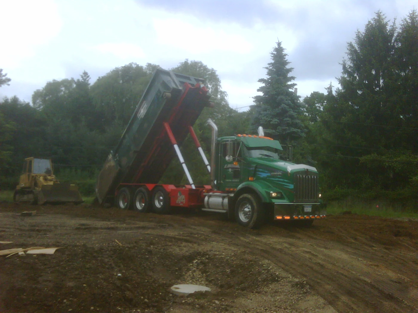 Roll-off truck delivering a dumpster to a construction site